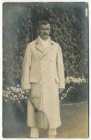 Charles Percy Dixon. Rare original sepia real photograph postcard of Dixon, standing full length, wearing tennis attire and a ‘Owe-Forty’ or blanket coat (worn to and from the court) and holding a racket in front of the ivy clad entrance to centre court 