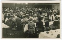 ‘Wimbledon 1914’. Rare original mono real photograph postcard showing the many spectators enjoying lunch outdoors, long table clothed tables with waitresses serving, ladies in hats and men in boaters etc. Card no. 077 in a series issued by Edwin Trim & Co