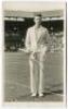 John Donald Budge. Original mono real photograph postcard of Budge, standing full length, wearing tennis attire and blazer at the net at Wimbledon and holding a racket. Players name printed to lower border. Card no. V82 in a series issued by Edwin Trim & 