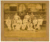 ‘The Australians 1884’. Original sepia photograph of the Australian team who played Lord Sheffield’s Eleven at Sheffield Park, East Sussex on the 12-14th May 1884, standing and seated in rows wearing blazers, caps and cricket attire. The photograph laid d