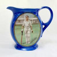 Herbert Sutcliffe. Yorkshire & England 1919-1945. New Hall Pottery blue water jug, printed with an oval colour portrait of Sutcliffe walking out to bat with stands to background, printed signature below. Crossed bats, stumps and cricket balls on crest to 