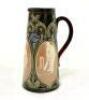 Doulton Lambeth tall tapering stoneware jug with three moulded relief vignettes of cricketers, a batsman, bowler and wicket keeper, Abel, Woods and McGregor in white on a brown background. With stylised floral leaf and daisy flower Art Nouveau decoration 