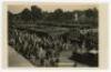 ‘Wimbledon. Promenade & Courts’. circa early 1920s. Original mono real photograph postcard showing showing a general overhead view of the courts at Wimbledon, with walkways, plan of matches on fencing divide and crowds of spectators. Card no. A.131 in a s