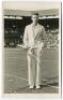 John Donald Budge. Original mono real photograph postcard of Budge, standing full length, wearing tennis attire and blazer at the net at Wimbledon and holding a racket. Players name printed to lower border. Card no. V82 in a series issued by Edwin Trim & 