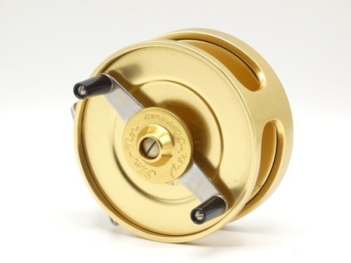 A Fin-Nor No.3 anti-reverse salt-water fly reel and spare spool, gold anodised finish, right hand wind model with twin ebonite handles mounted on alloy cross bar winding arm above a milled tension wheel, polished alloy foot, fixed check mechanism, as new
