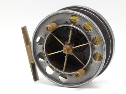 An Allcock Aerial 4" model 7950-T6 centre pin reel, caged and six spoked drum with twin xylonite handles, perforated front flange (eight holes) and twin regulator/release forks, brass stancheon foot, rear sliding optional check button and bar spring check