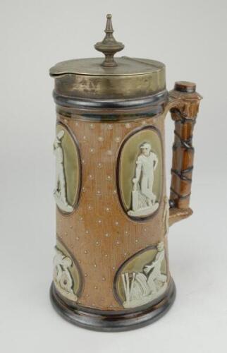 Cricketing jug. A large and impressive Doulton Lambeth stoneware tapering jug, moulded in relief with six raised figures, three of batsman, two of fielders and a wicket keeper in roundels, all different and in various positions. With two further smaller r