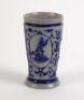 Westerwald stoneware cricket beaker, moulded in relief with three cameo panels of a batsman, after W.G. Grace, in different poses. The body decorated with vine and sprig decoration in cobalt blue on a grey background. Blue rings to rim and to foot. Approx