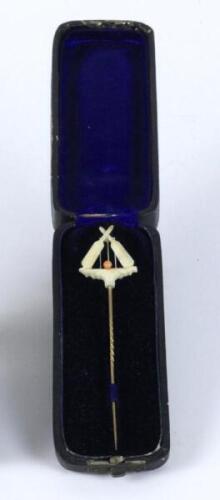 Cricket stick pin. A Victorian gold lapel stick pin with ornate crossed bats, wicket with bails and ball mounted on a naturalistic small platform to head, appears to be have been carved from ivory (?). The pin measures 3.75” long and is presented in its o