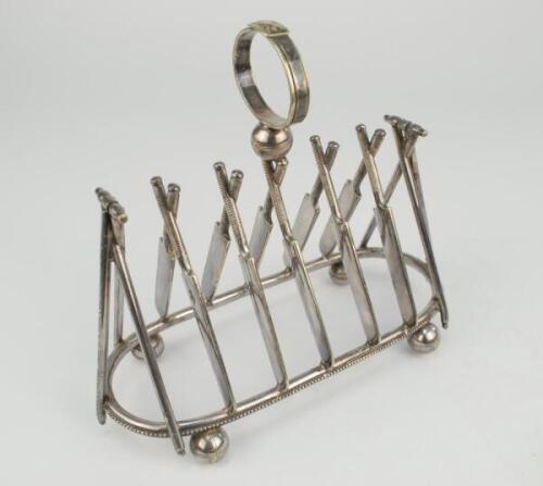 Cricket toast rack c1900. A Victorian silver plated, six division toast rack with five pairs of stumps and bails to centre, with set of angled cricket stumps and bails at each end, the handle in the form of a cricketer’s belt and buckle on a cricket ball.