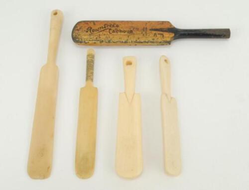 Miniature cricket bats. A worn ‘Rowntree’s Cachous’ miniature metal advertising cricket bat. 4.5”. Sold with four miniature ivory cricket bats. One 5”, one 3.75” long and two 3.5” long. Three of the bats with holes to ends. Probably c1950s. Good condition