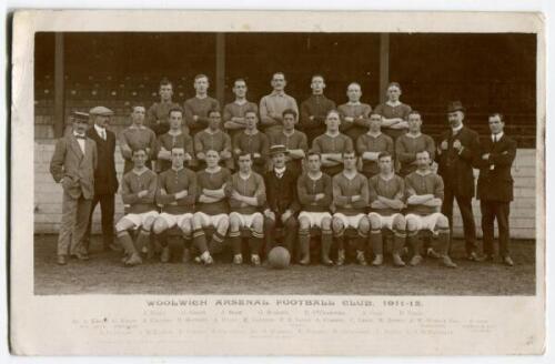 Woolwich Arsenal Football Club 1911-12’. Mono real photograph postcard of the Woolwich Arsenal team, staff and directors standing and sitting in rows in front of the stand. Title and players names printed to lower border. Postally used and dated 1911. A r