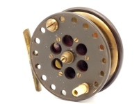A scarce Allcock No.2 Schooling 3 ½" centre pin reel, brass backed drum with perforated ebonite front plate, counter-balanced tapered ivorine handle, milled brass tension nut and ported wooden arbour, brass starback foot with sliding optional check butto