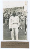 Learie Nicholas Constantine. Trinidad, Barbados & West Indies 1921-1939. Scarborough 1928. Original mono real photograph postcard of Constantine depicted almost full length standing on the outfield at Scarborough with spectators in the background. Officia