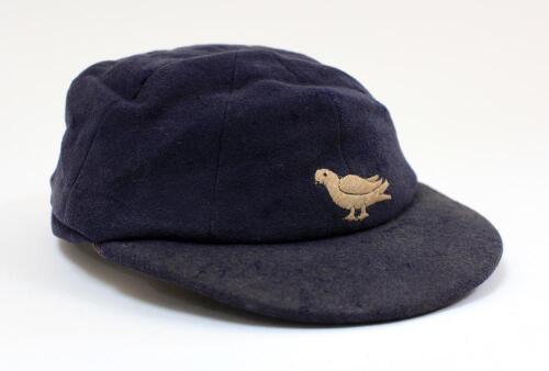 Sussex navy blue 2nd XI cloth cricket cap worn by Robin Marlar during his playing career. The cap, by W.V. Brown of Eton, embroidered with the single martlet emblem of Sussex to front. The cap is worn and a little faded, with odd faults, odd moth hole etc