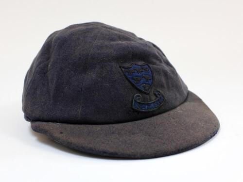 Sussex navy blue 1st XI cloth cricket cap worn by Robin Marlar during his playing career. The cap, by W.V. Brown of Eton, with wired Sussex emblem of the six martlets to front. The cap and emblem are worn and faded, with odd faults, odd moth hole etc othe