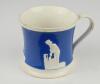 Staffordshire blue ground waisted cricket mug with strap handle and beaded rim. With three relief moulded figures of a batsman, bowler and wicket keeper in cream, believed to be Lillywhite, Pilch and Box. c1860. Very minor wear to rim, minor wear to base 