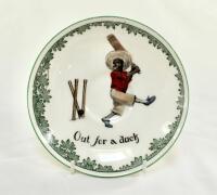 &lsquo;Out for a Duck&rsquo; Royal Doulton Black Boy saucer, entitled &lsquo;Out for a Duck&rsquo; printed with a boy cricketer in red shirt and a floppy hat in batting pose having attempted a big shot, looking back to see the ball hit his wicket. Green floral decoration to edge