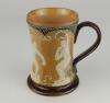 Doulton Lambeth stoneware waisted body tankard with art noveau designs of stylised hearts and white on blue dots, with sporting figures in relief in white showing two footballers with ball, athletics runner and shot putting. 6&rdquo; tall. Impressed Doulton Lam