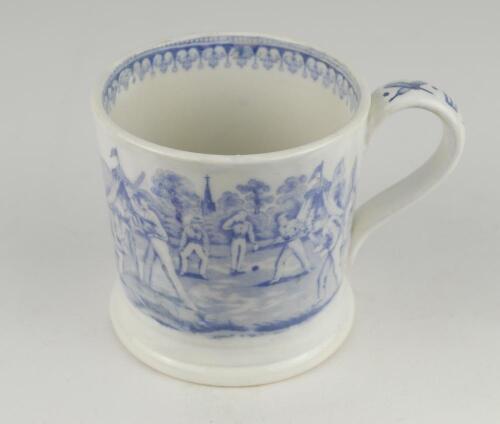 Village cricket mug. Staffordshire 19th century mug, transfer printed in pale blue with two scenes of village cricket to either side, with church and tents to background, floral and oak leaf rim decoration and crossed cricket bats, balls and stumps decora