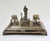 Cricket desk set. Large and impressive silver plated cricket ink stand consisting of a central detachable section with figure of a batsman posed in front of the wicket to lid, two glass ink pots with plated lids on a oblong stand with pen rests to both si