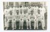 Hampshire C.C.C. 1937. Original mono real photograph plain back postcard of the 1937 Hampshire team seated and standing in rows wearing cricket attire in front of the pavilion. Ex John Arlott collection with title and players’ names neatly annotated in Ar