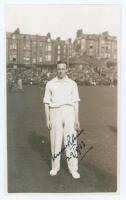 Robert Walter Vivian Robins. Middlesex, Cambridge University & England 1926-1951. Mono real photograph postcard of Robins standing full length on the field at Scarborough with crowded stands in the background. Signed in black ink to the photograph by Robi