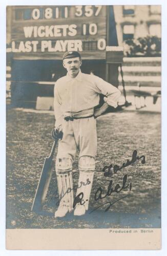 Robert &lsquo;Bobby&rsquo; Abel. Surrey & England 1881-1904. Early sepia real photograph postcard of Abel standing full length in front of the scoreboard, wearing cricket attire, leaning on his bat. The scoreboard depicts Abel&rsquo;s highest first-class score of 357no whe