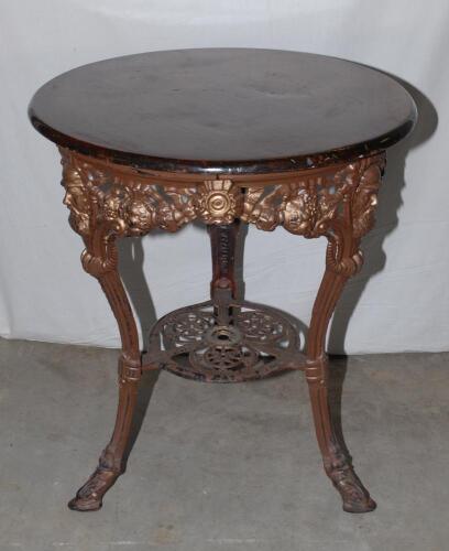 W.G. Grace. Original cast iron circular public house table with circular wooden top, supported by three legs, moulded with portrait busts of Grace wearing cricket cap to top of each leg with imprinted initials &lsquo;W.G&rsquo; above, and decorated pierced apron of b