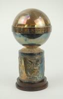 ‘England tour of Sri Lanka 1982’. Decorative silver metal commemorative chalice. The lid in the shape ball with title to rim, decorative base with panels of ornate birds/ducks? to sides of base. The chalice stands on a small wooden base. Approximately 9” 