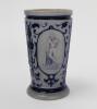 Westerwald stoneware cricket beaker, moulded in relief with three cameo panels of a batsman, after W.G. Grace, in different poses. The body decorated with vine and sprig decoration in cobalt blue on a grey background. Blue rings to rim and to foot. Approx