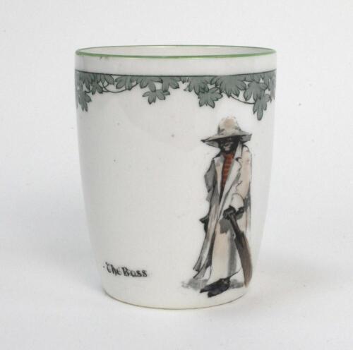 ‘The Boss’. A Royal Doulton ‘Black Boy’ bone china Burke beaker, entitled ‘The Boss’ printed with a boy in red shirt and a floppy hat, wearing an umpires’s coat and holding a bat, ‘The All Black Team’ crest to verso. Green floral decoration to top rim. 4”