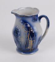 Cricket jug. Victorian Staffordshire blue glazed ceramic jug decorated in relief with a figure of a batsman in front of the wicket, with bushes and a house to background to one side and a gentleman cycling to the other. Floral and bird decoration. The jug