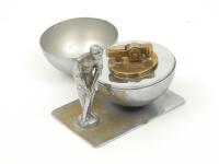 Cricket cigarette lighter. White metal table lighter consisting of a batsman wearing a cap in batting stance along side a large mounted cricket ball which is hinged and opens to reveal the lighter, the two items mounted to a flat base. Approximately 3.5”x