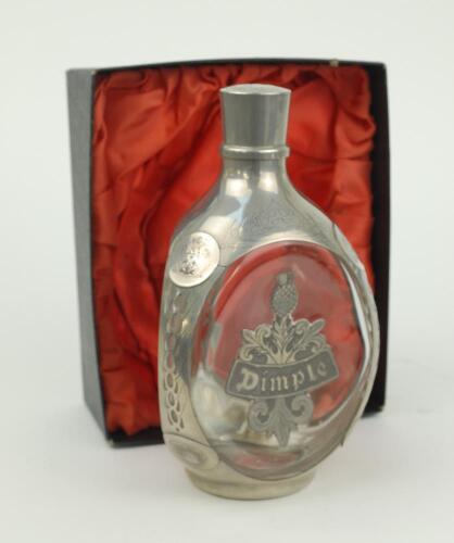 E.W. ‘Jim’ Swanton. Glass and pewter ‘Haig Dimple’ whisky decanter with ‘Dimple’ motif pewter panel to one side, with floral decorations, ‘Haig’, and coats of arms to sides. Maker’s mark for Daalderop Royal Holland Pewter, no. N4919 to base. 8.5” tall. Ac