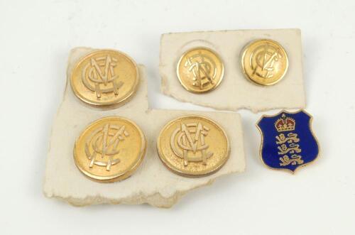 Cricket buttons. A selection of five gold metal M.C.C. blazer buttons, three large for the front of the blazer and two small for the sleeve. Sold with a England ‘three lions and the crown’ pin badge. G