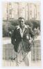 Maurice William Tate. Sussex & England 1912-1937. Original mono real photograph postcard of Tate standing three quarter length in front of railings at Scarborough, wearing cricket attire and England blazer. Nicely signed in ink to the photograph by Tate. 