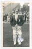 Stewart Cathie ‘Billy’ Griffith. Cambridge University, Surrey, Sussex & England 1934-1954. Original mono real photograph postcard of Griffith standing full length on the outfield at Scarborough, wearing M.C.C. tour blazer and wicket-keeping pads. Signed i