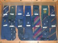 Cricket ties. A selection of fourteen cricket ties in a glass fronted wooded display case. Fourteen ties including England home Test tie, England touring tie, M.C.C. ‘City’ tie, Australia tour of New Zealand players 1977 tie, Australia World Cup 1975 tie,