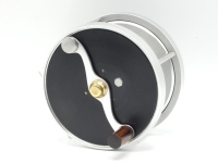 A fine Ted Godfrey Salmon III direct drive salmon fly reel, left hand wind model with black anodised end plates, serpentine counter-balanced rosewood handle, bridge foot, triple cage pillars, rear off-set ten point graduated tension adjuster and milled a