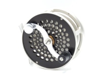 A fine S.E. Bogdan Steelhead 3 ¼" fly reel, left hand wind model with black/silver anodised finish, counter-balanced serpentine crank handle set within an anti-foul rim, pierced foot, multi-perforated drum and faceplate, fixed click check mechanism, rear