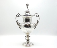 A fine sterling silver Chertsey Angling Association trophy cup, the twin handled, lidded urn shaped cup profusely engraved with angling scenes and running fish and acanthus border panels, twin scrolled handles each with fish application and fluted lid wit