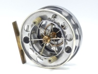 A good Allcock Aerial model 7950-T3 narrow drummed 4" centre pin reel, nickel silver rimmed caged and six spoked drum with twin xylonite handles, perforated front flange (eight holes) and twin release regulator forks, brass stancheon foot, milled circula