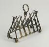 Cricket toast rack c1900. A Victorian silver plated, six division toast rack with five pairs of crossed cricket bats, with a set of angled cricket stumps and bails at each end, the handle of the rack in the form of a cricketer’s belt and buckle on a crick