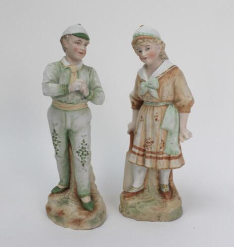 ‘Young England and Young England’s sister’. Very large pair of continental bisque figures of a boy, wearing white and green cap holding a cricket ball and a young girl, also wearing a white, green and brown cap, dressed in three-quarter dress holding a cr