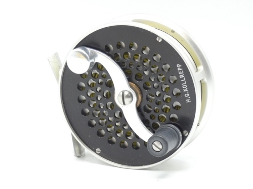 A scarce S.E. Bogdan Trout 5wt fly reel, left hand wind model with silver/black anodised finish, counter-balanced serpentine crank handle, pierced foot, fixed click check mechanism, multi-perforated drum and faceplate, rear milled spindle cap and applied 