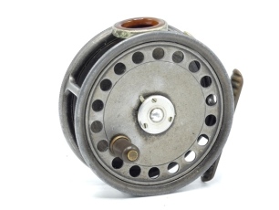 A rare Hardy St George 3 3/8" left hand wind trout fly reel, shallow cored drum with ebonite handle and three screw spring latch, ribbed brass foot, unusual amber agate line guide (no cracks), milled rim tension screw and Mk.II check mechanism, light wear