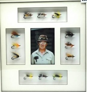 A framed display of twelve "Rat" pattern hair wing salmon flies, tied by Edmund de Ste Croix of Gaspe, Quebec various patterns including, Rusty Rat, Silver rat, Bette-Jane, St. John rat, Gaspe Rat et al, mounted in shadow box frame with central image of