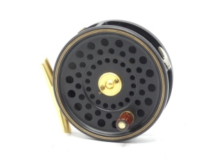 A Hardy Pall Mall Centenary rod and reel set, comprising #6/7 trout fly reel with black/gold anodised finish, rose wood handle, two screw spring drum latch, brass foot, rim tension screw and dual compensating check mechanism, new/unused, in Selvyt bag and