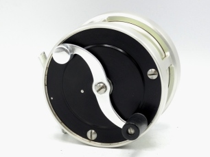 An S.E. Bogdan Model 2 multiplying salmon fly reel, black/champagne anodised finish right hand wind model with counter-balanced "S" scroll handle set within an anti-foul rim, block foot, rear milled optional check button and off-set ten point graduated te